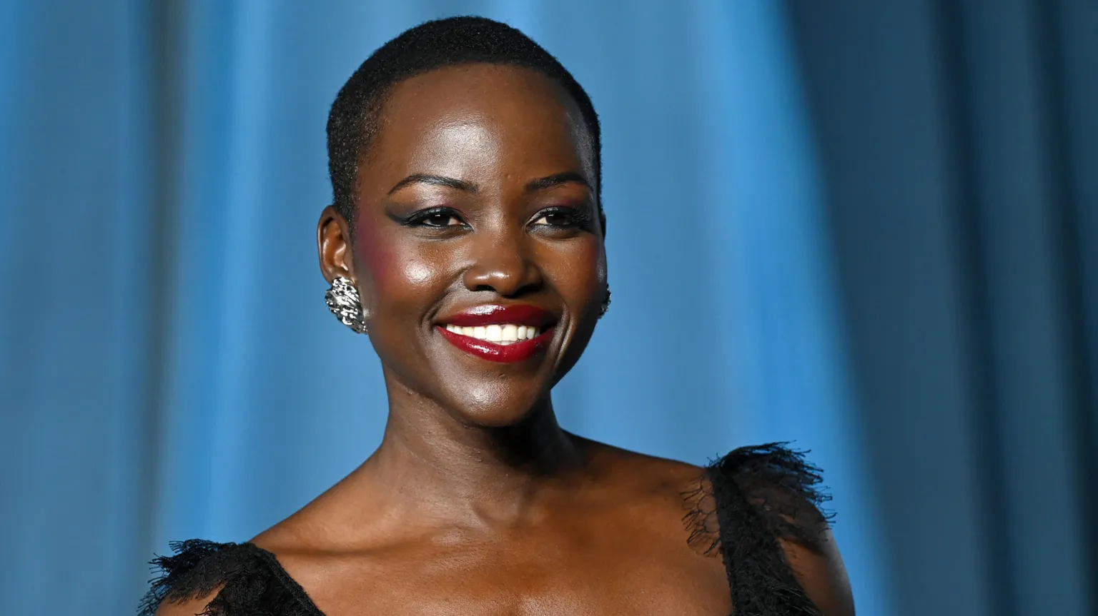 Getty Images Lupita Nyong'o smiling and wearing a black dress, posing for photos at the Academy Museum of Motion Pictures in Los Angeles in October 2025